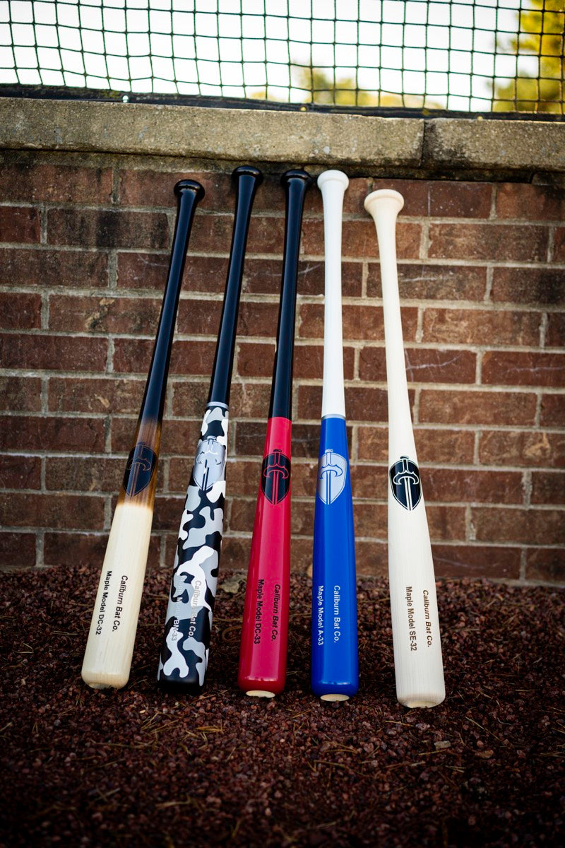 Five Caliburn maple bats lined up against a brick wall