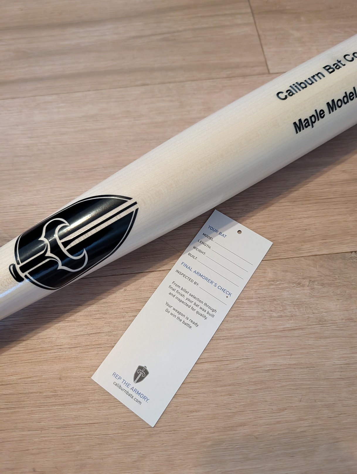 Caliburn bat with the Armory hang tag, back side showing bat details and final inspection sign-off